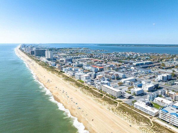 Vista aérea de una ciudad costera con playa, edificios y un puerto deportivo.