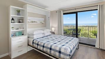 Ein Schlafzimmer mit Bett, Nachttisch, Kommode und einem Balkon mit Meerblick.