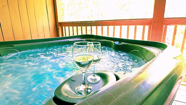 A hot tub with two glasses of wine. - Snuggle Bear: Cozy, Enchanting Mtn. Retreat Haven. New Renovated & deep cleaned! (Gatlinburg)