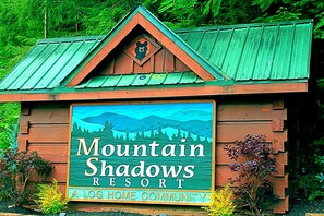 A wooden cabin with a green roof and a sign that reads "Mountain Shadows Resort". - Snuggle Bear: Cozy, Enchanting Mtn. Retreat Haven. New Renovated & deep cleaned! (Gatlinburg)