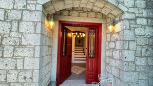 A stone archway leading to a red door with a staircase inside. - Armi Alaçatı (Cesme)
