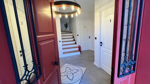 A hallway with a staircase, a decorative light fixture, and a patterned rug. - Armi Alaçatı (Cesme)