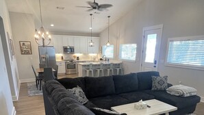 A modern living room with a dark sectional sofa, two white coffee tables, and a patterned rug. - BRAND NEW Beach House with Gulf Views! Less than 3 min walk to the beach! (Gulfport)