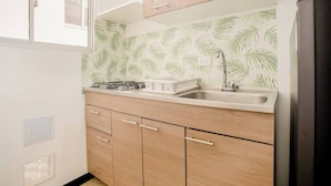 A kitchen with a gas stove, a sink, and wooden cabinets. - Hotel Natural Sevgi (Bogotá)