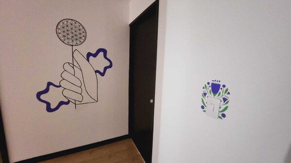 A hallway with a handprint artwork on the left wall and a logo on the right wall. - Hotel Natural Sevgi (Bogotá)