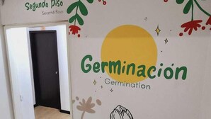 A hallway with a sign for "Segundo Piso" and "Germinación" on the wall, leading to a door. - Hotel Natural Sevgi (Bogotá)