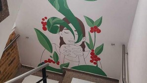 A staircase with a hand-painted mural featuring a sun, clouds, and foliage. - Hotel Natural Sevgi (Bogotá)