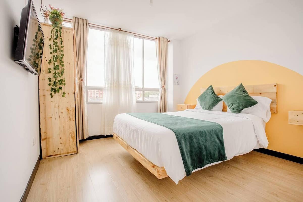 A room with a bed, curtains, a TV, and a window.
