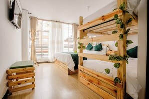 A bunk bed room with a wooden headboard, a small bench, and a window with curtains. - Hotel Natural Sevgi (Bogotá)