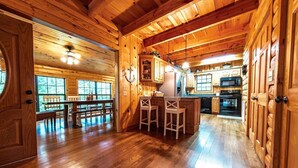 Interior de una cabaña de madera con comedor, cocina y asientos en la barra.