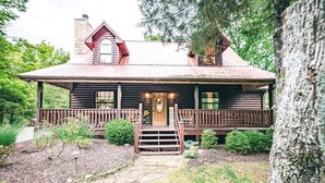 Una cabaña de troncos con un porche, una chimenea y una puerta que dice "CABIN".