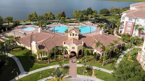 Ein Resort mit einem zentral gelegenen Pool, einem Tennisplatz und Blick auf einen See.
