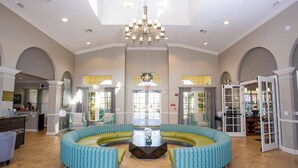 Eine geräumige Lobby mit einer zentralen Sitzecke, einem Chandelier und einer Rezeption.