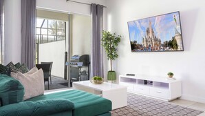 Un salon moderne avec un canapé vert, une table basse blanche et un téléviseur à écran plat fixé au mur.