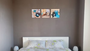 A bedroom with a bed, two bedside tables, and three wall-mounted pictures. - Maison Sécurisée à 2km de la Plage et du Centre-ville (Soulac-sur-Mer)