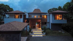A modern house with a central entrance, two side wings, and a covered patio area.