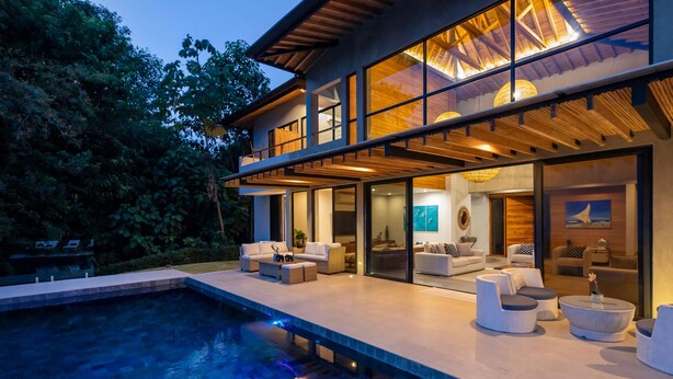A modern house with a pool, outdoor seating, and large windows.
