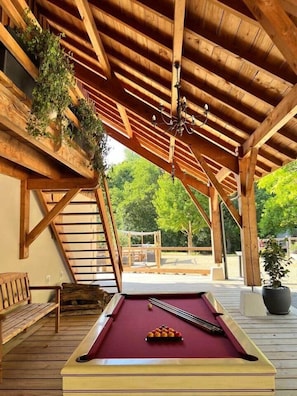 A wooden deck with a pool table, benches, and a hanging plant. - Le Moulin D'hourtoy Entre Forêt er Rivières (hourtoy)