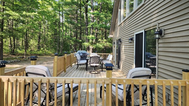 A deck with outdoor furniture, a grill, and a wooden fence.