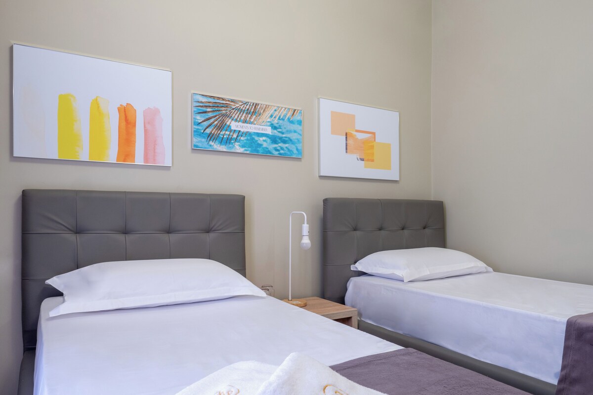 A hotel room with two beds, a nightstand, and wall art.