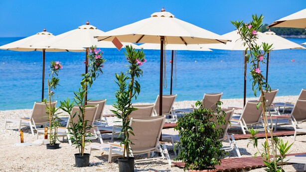 A beachside seating area with umbrellas and lounge chairs. - Nia Boutique Hotel by Rapos Resort (Himarë)
