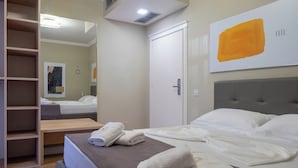 A hotel room with a bed, a bedside table, a wardrobe, and a large mirror. - Nia Boutique Hotel by Rapos Resort (Himarë)