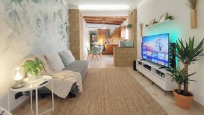 Un salon avec un canapé, une télévision et des plantes en pot.