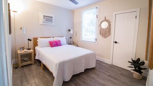 A bedroom with a bed, bedside table, ceiling fan, window, and door. - The Downtown Hibiscus House (West Palm Beach)