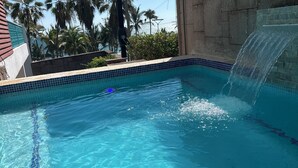 A clear blue pool with a waterfall feature, surrounded by a tiled edge and a concrete wall. - 4,000 sq ft 6 bed ocean Villa w/housekeeping included!! (Mazatlán)