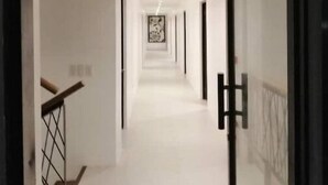 Ein moderner Flur mit Glastür, einer Treppe und einem gerahmten Kunstwerk an der Wand.
