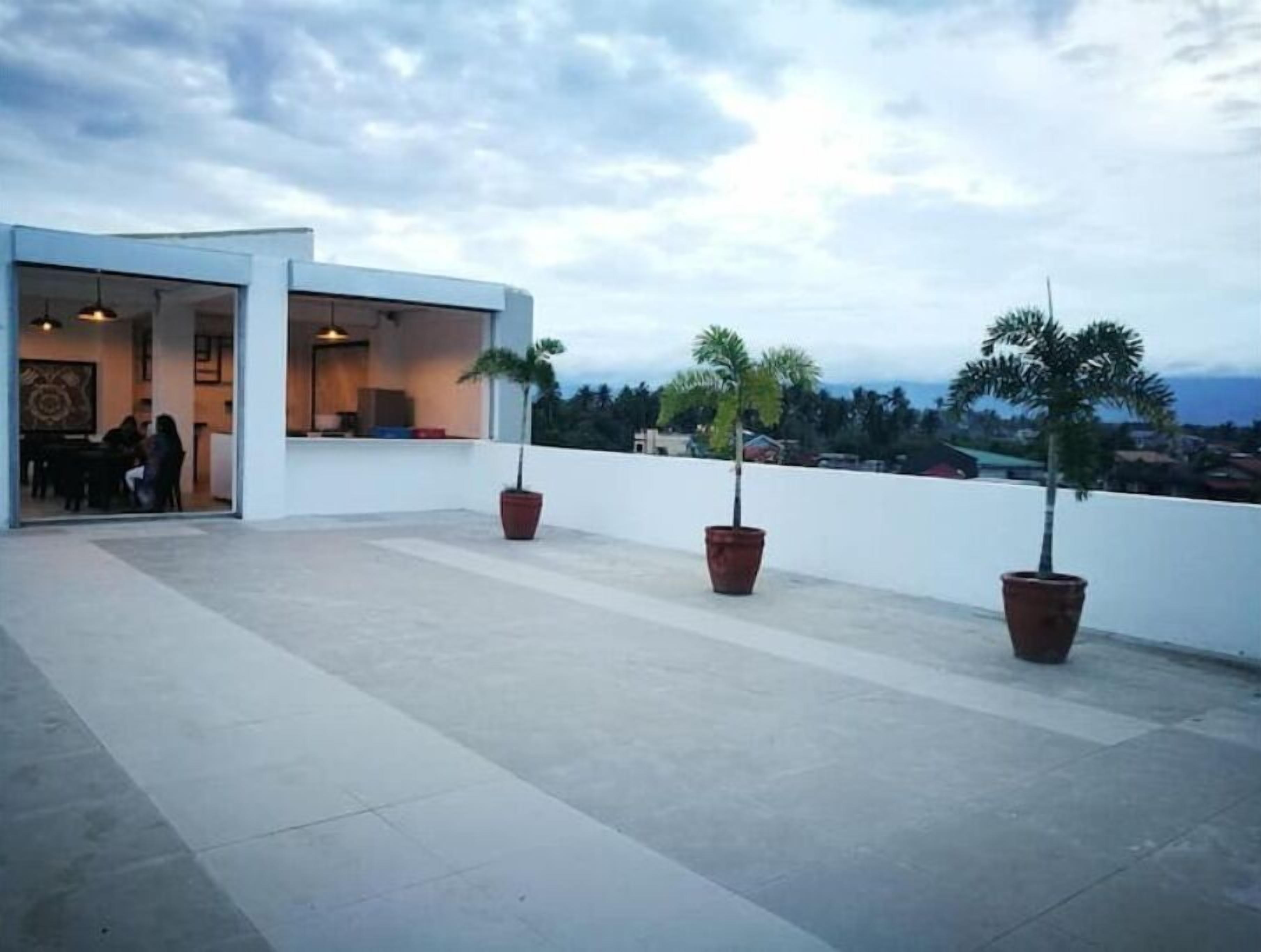 Una terraza en la azotea con plantas en macetas, un comedor y vistas a la ciudad.