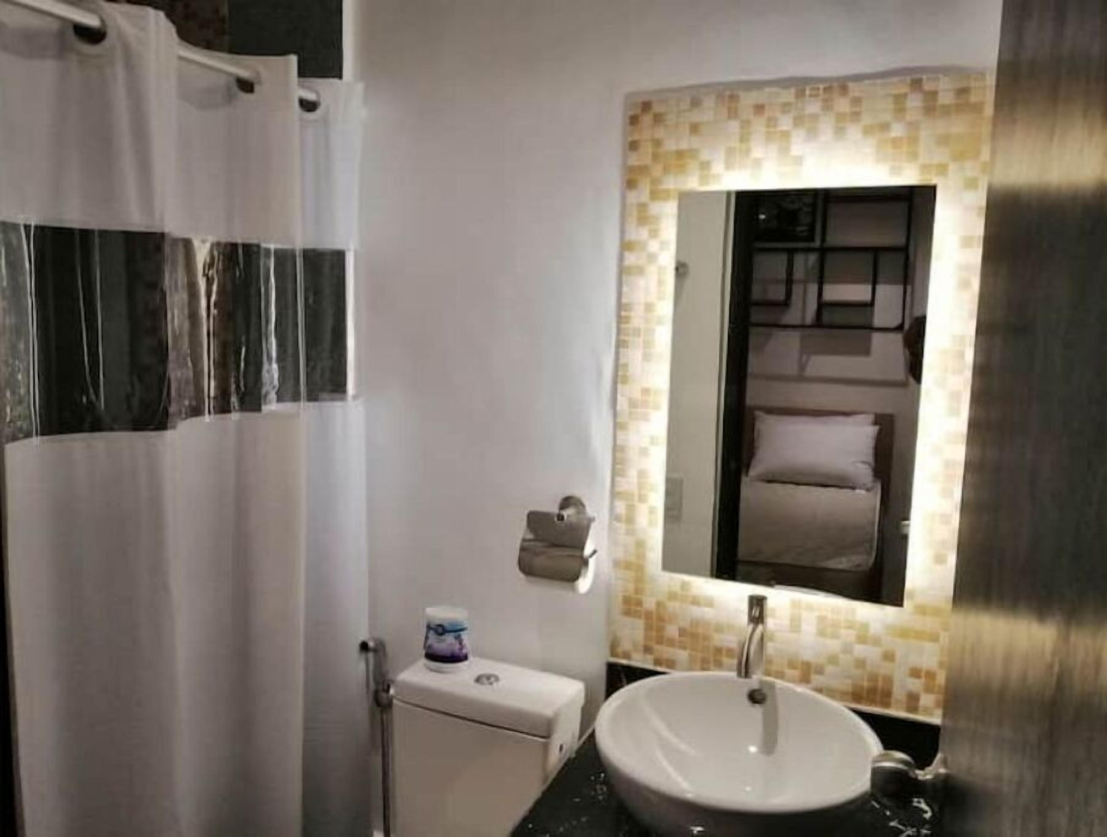 A bathroom with a white toilet, a sink with a mirror above it, and a shower curtain.