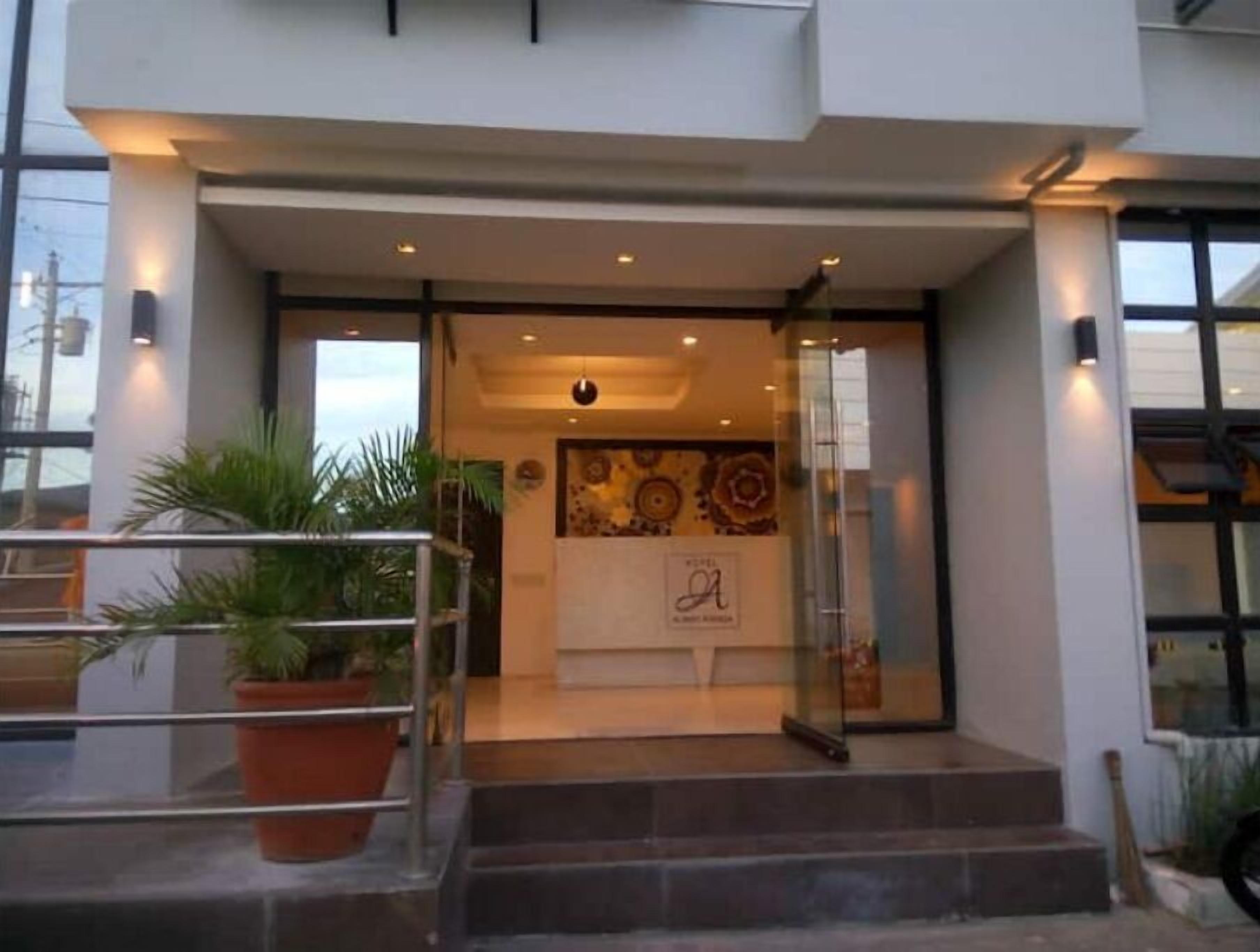Une entrée d’hôtel moderne avec une porte en verre, un pot de fleurs et un escalier menant à l’entrée.