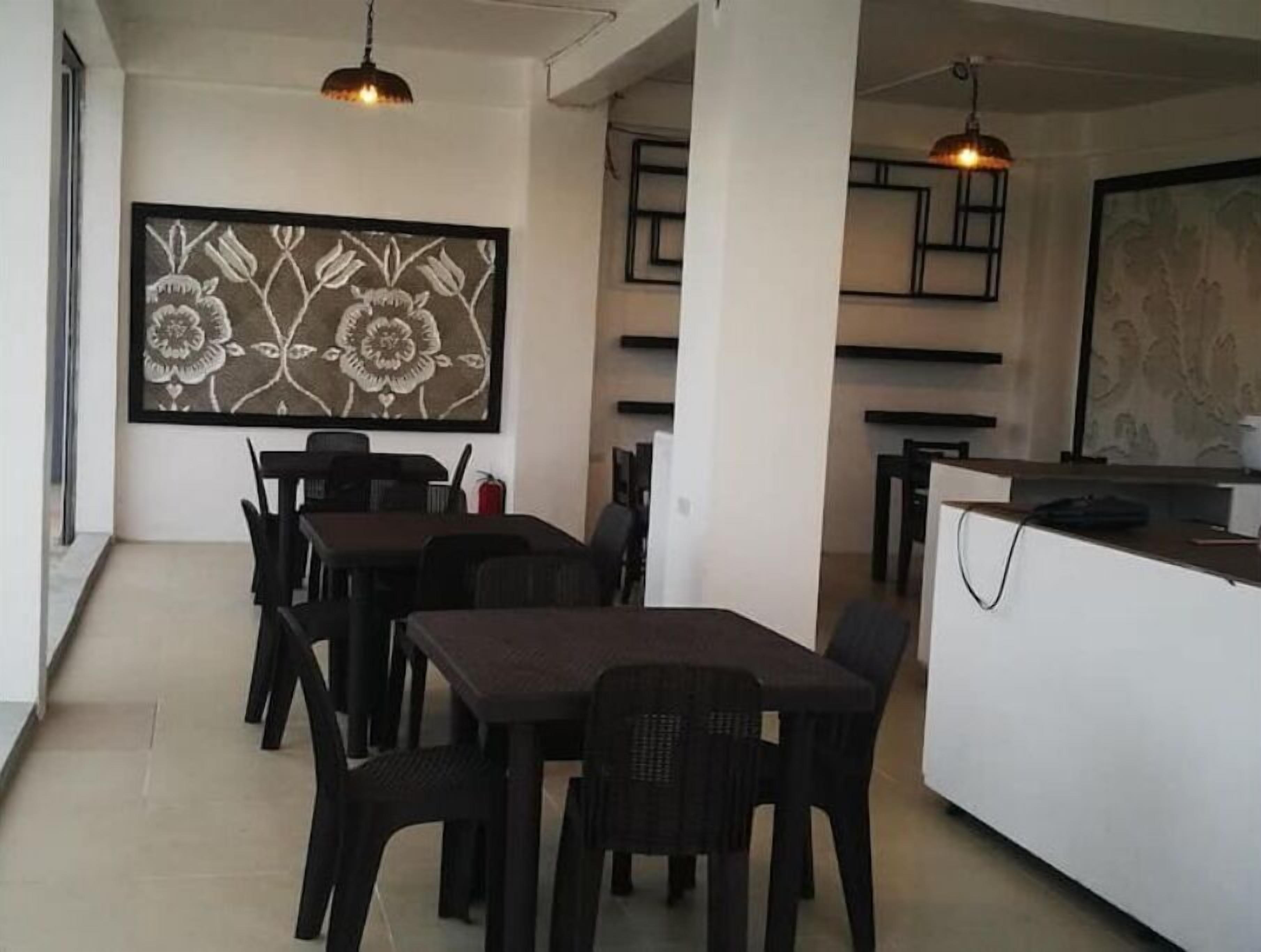 A modern dining area with a long table and chairs, a white counter, and a large floral artwork on the wall.