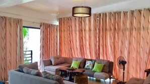 A living room with a sofa set, a coffee table, and a floor lamp. - Casa Herminia Second Floor Studio with Balcony (Baler)
