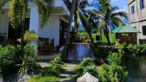 Un bâtiment moderne à deux étages, doté d’une piscine et agrémenté d’une végétation tropicale luxuriante.