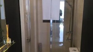 A compact bathroom with a white sink, toilet, and glass-enclosed shower.