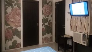 A room with a bed, a TV, and a wall-mounted air conditioner.