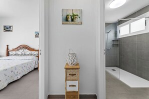 Un dormitorio con una cama, una mesita de noche con lámpara y un cuadro en la pared.
