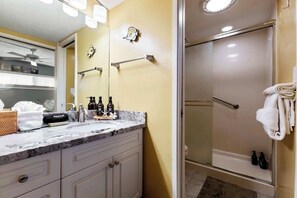 Uma casa de banho com lavatório, chuveiro e porta-toalhas.