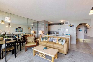 Een moderne woonkamer met een bank, salontafel, eethoek en keuken.