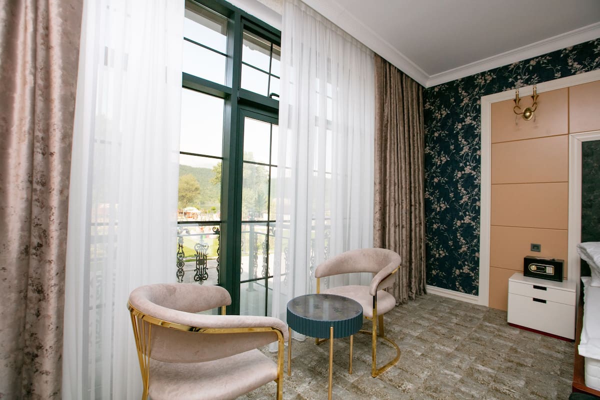Ein Zimmer mit zwei Stühlen, einem kleinen Tisch, einem weißen Nachttisch und einem Radio.