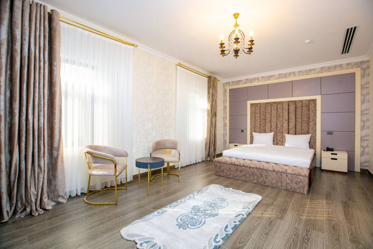 Ein modernes Schlafzimmer mit einem großen Bett, zwei Stühlen, einem kleinen Tisch und einer Chandelier.