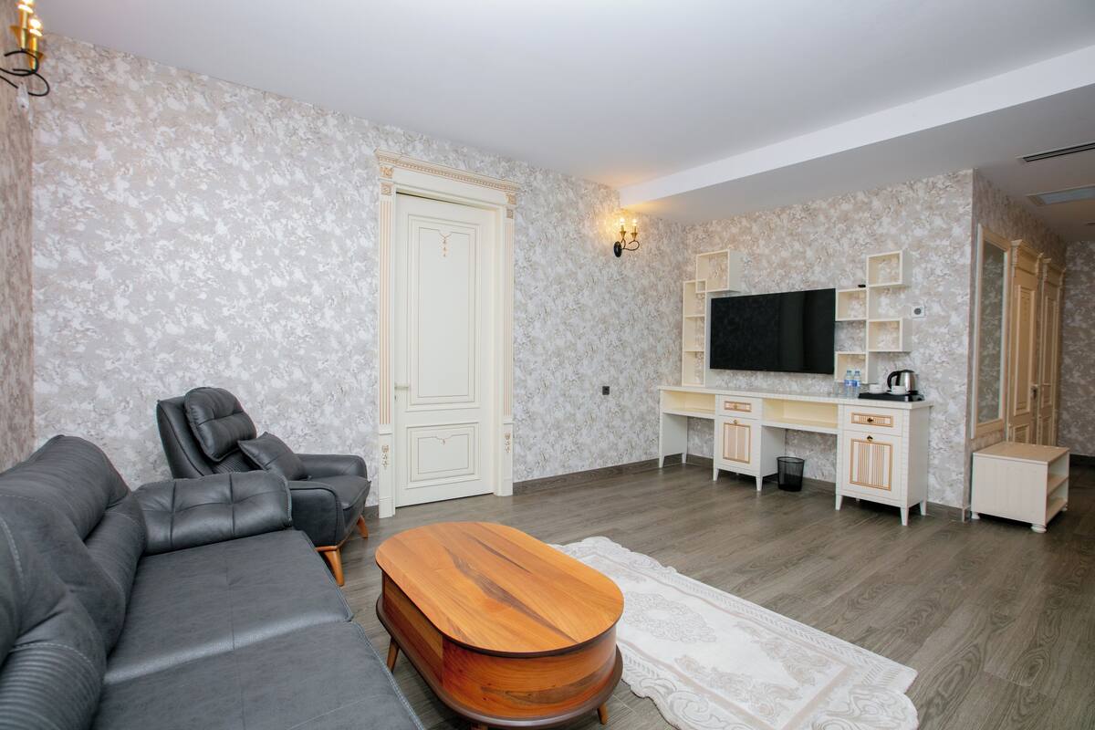 Ein Wohnzimmer mit einer Couch, einem Holztisch, einem Fernseher und einem Schreibtisch mit Stauraum.