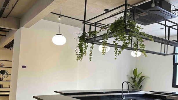 A modern kitchen with a central island, bar stools, hanging plants, and pendant lighting. - Beautiful Studio near Av Paulista and Sírio Libanês (Bela Vista São Paulo)