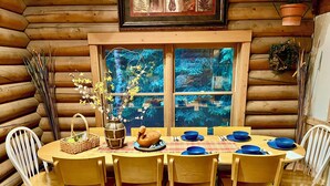 Ein Holzblockbau-Innenraum mit einem Esstisch, gedeckt für sechs Personen, umgeben von Holzstühlen.