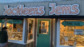 Une boutique appelée « Jackleens Jems », avec une porte verte et des vitrines.