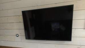Une table en bois foncé avec un téléviseur fixé au mur, qui est recouvert de panneaux blancs.