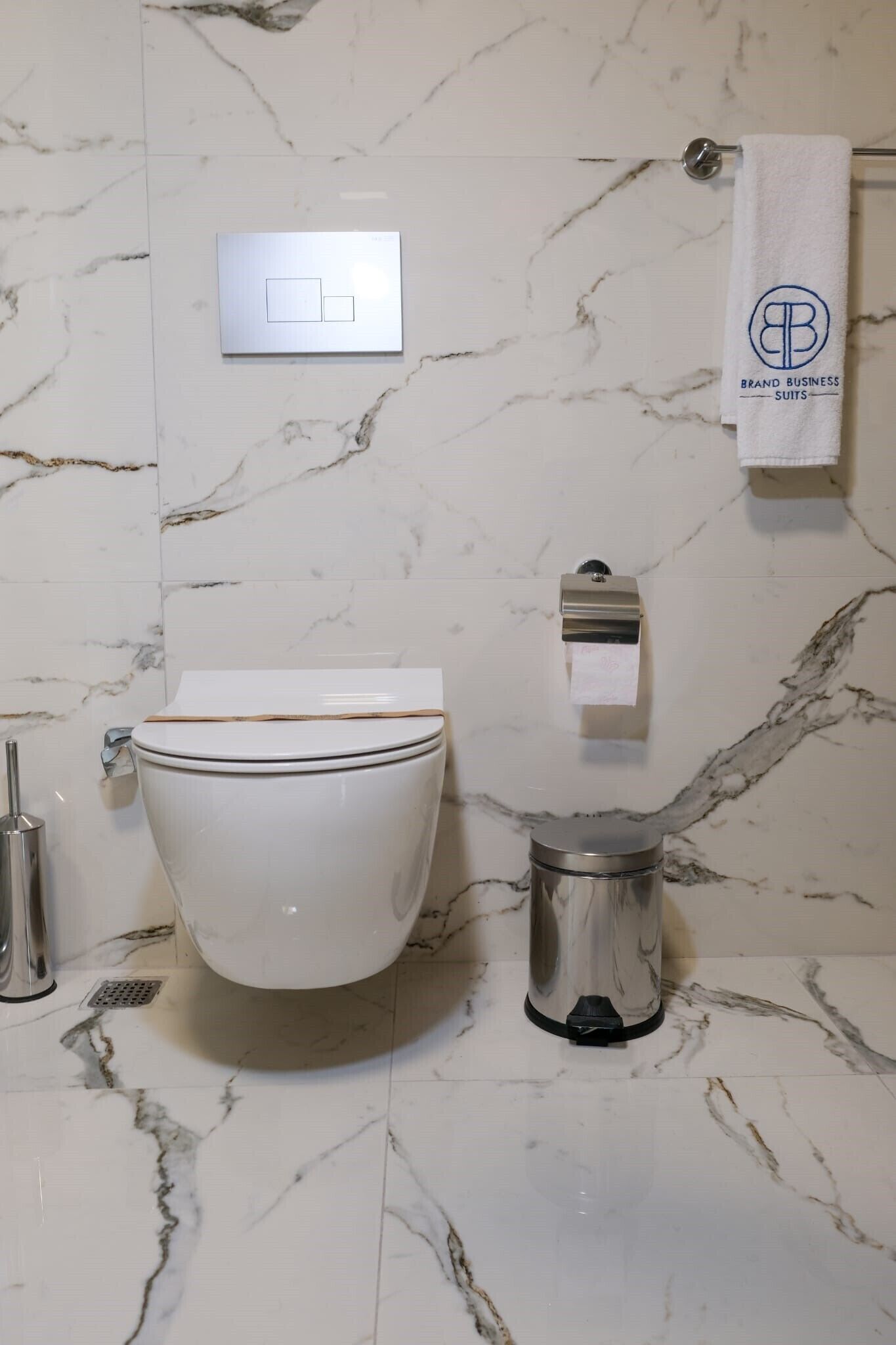 Un baño con inodoro, bidé, toallero y suelo de mármol.