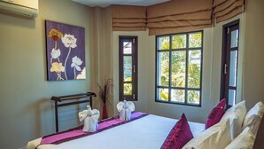 Een hotelkamer met een groot bed, een schilderij aan de muur en een raam met uitzicht op groen.
